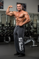 Thefreeway Art.254 unisex bodybuilding training pants in grey and black stripes worn by a male bodybuilder in a three-quarter flex pose at the gym