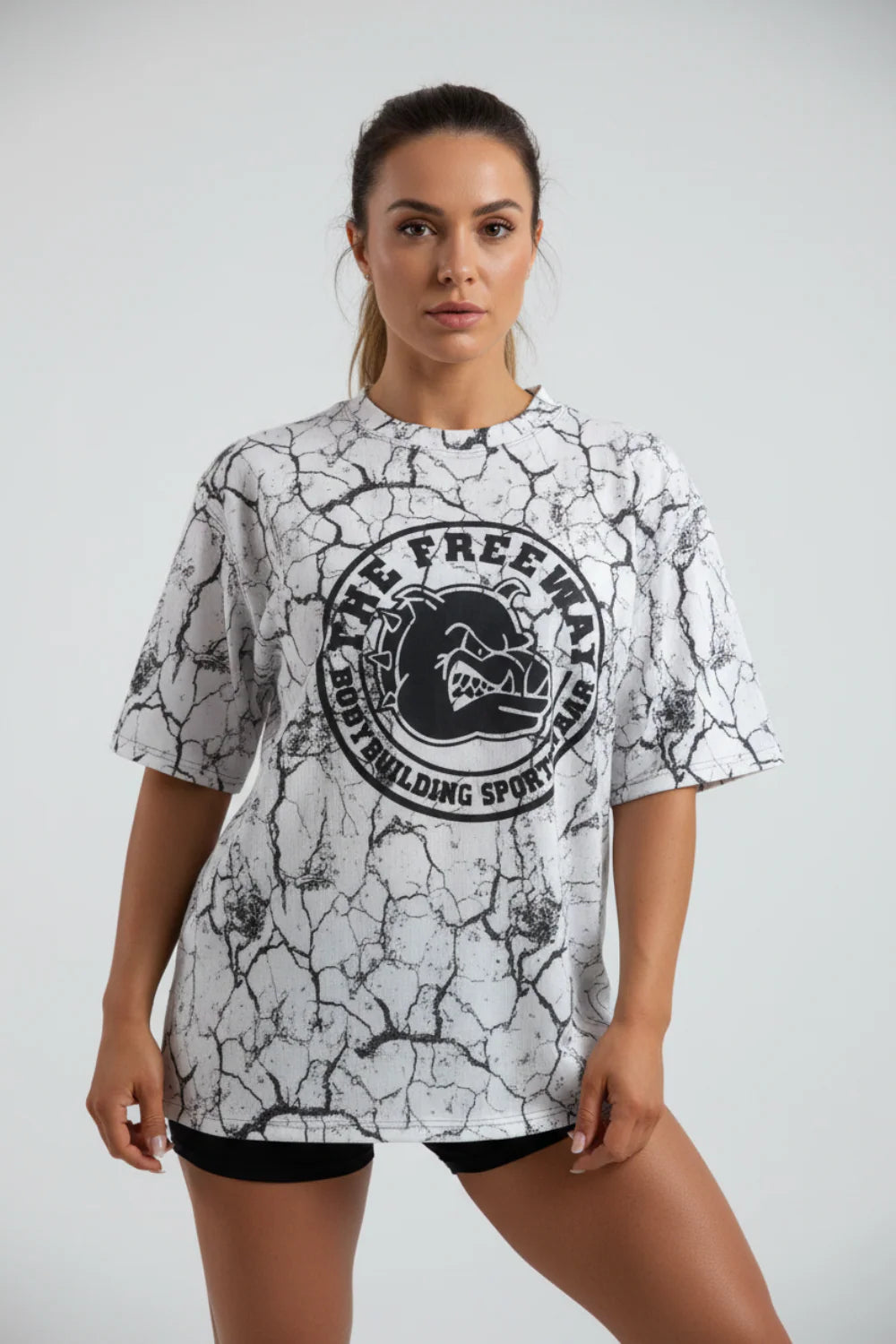 White marbled rounded bodybuilding rag top Thefreeway Sportswear art. 2272 worn by a female model in a straight front pose with large black logo